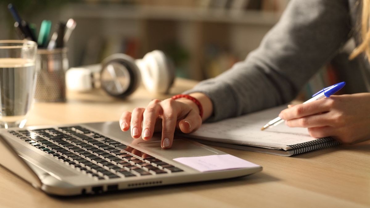 Close,Up,Of,Student,Girl,Hands,Comparing,Notes,On,Laptop