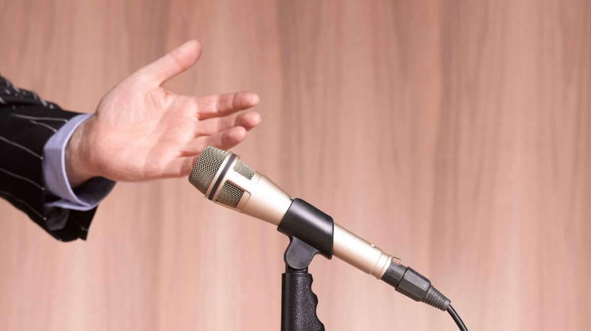 Hand and Microphone against wooden background.