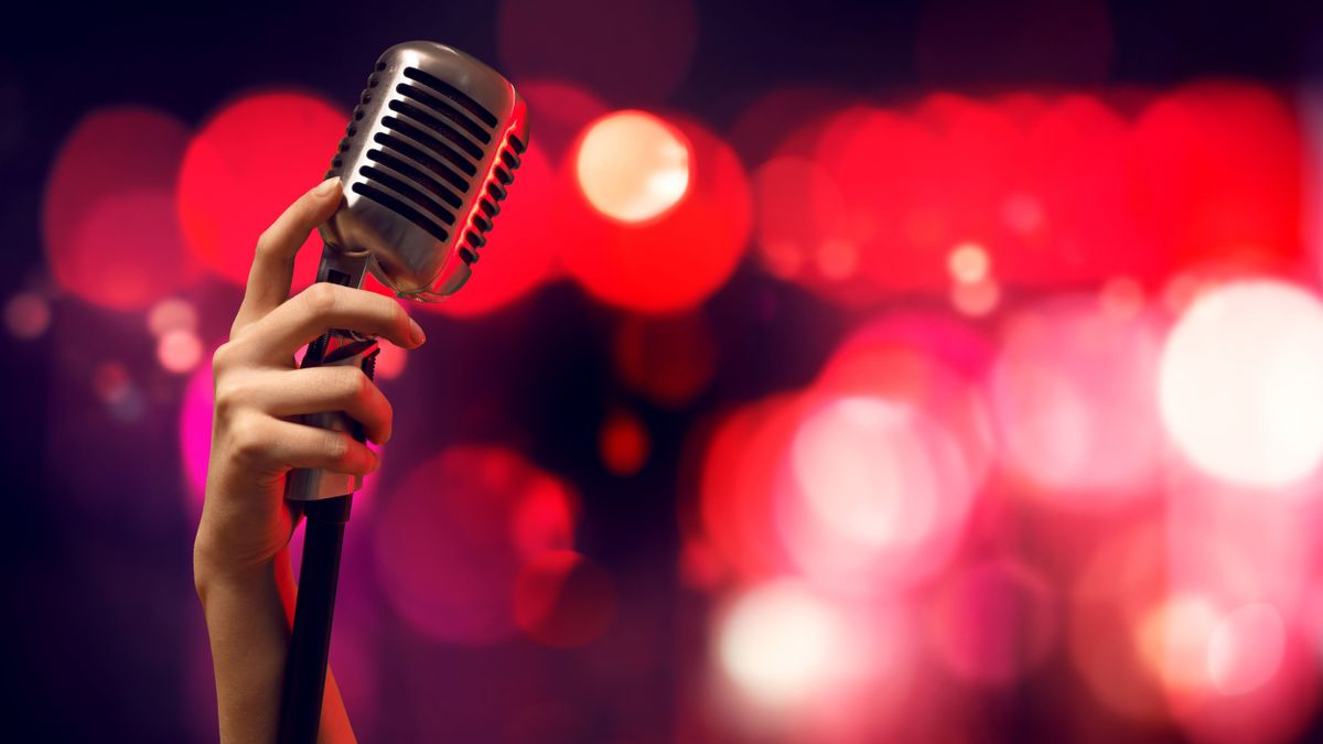 Close,Up,Of,Female,Hand,On,Blurred,Background,Holding,Microphone