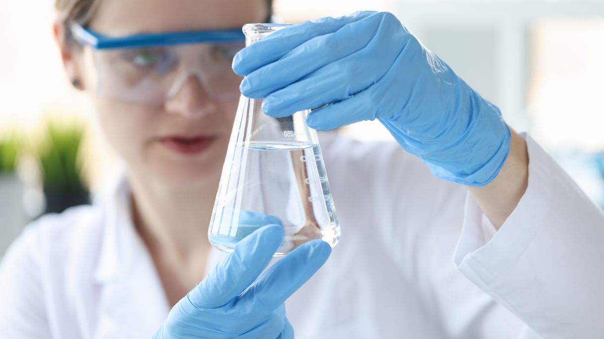 Woman,Scientist,Holding,Flask,With,Transparent,Liquid,In,Her,Hands