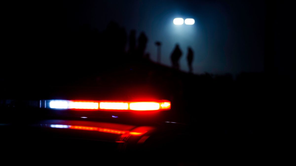 Police,Lights,Flash,As,People,Are,Silhouetted,In,The,Background