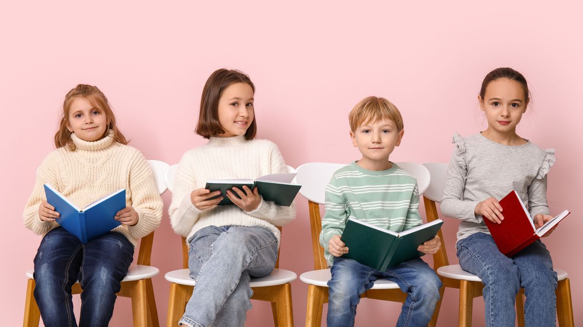 Little,Children,Reading,Books,While,Sitting,On,Chairs,Against,Pink