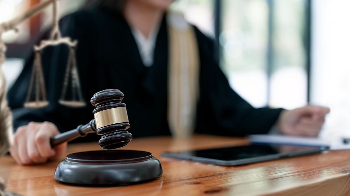 Woman judge hand holding gavel to bang on sounding block in the court room.