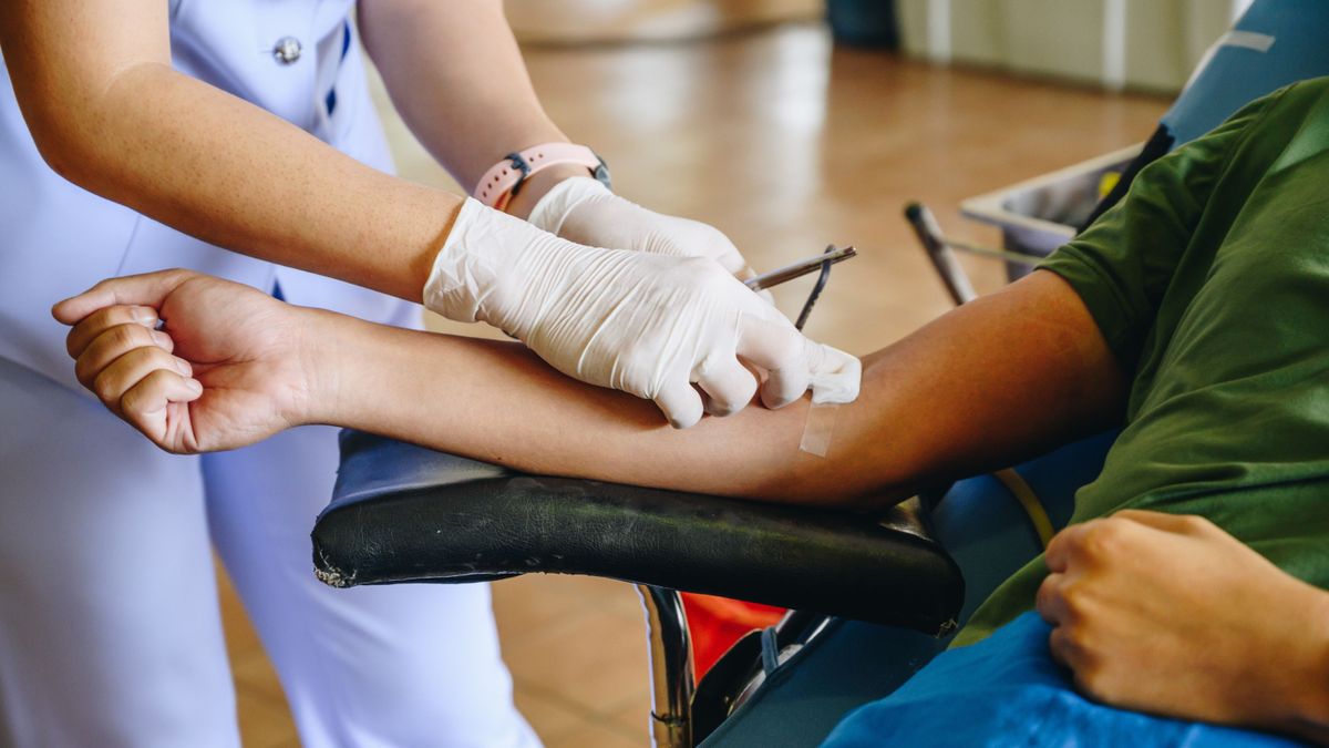 Nurse help patient to stop bleeding while donating blood.