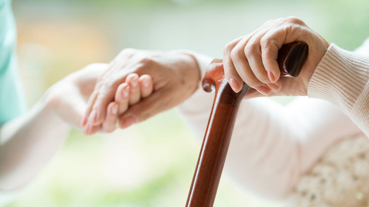 Elder,Person,Using,Wooden,Walking,Cane,During,Rehabilitation,In,Friendly