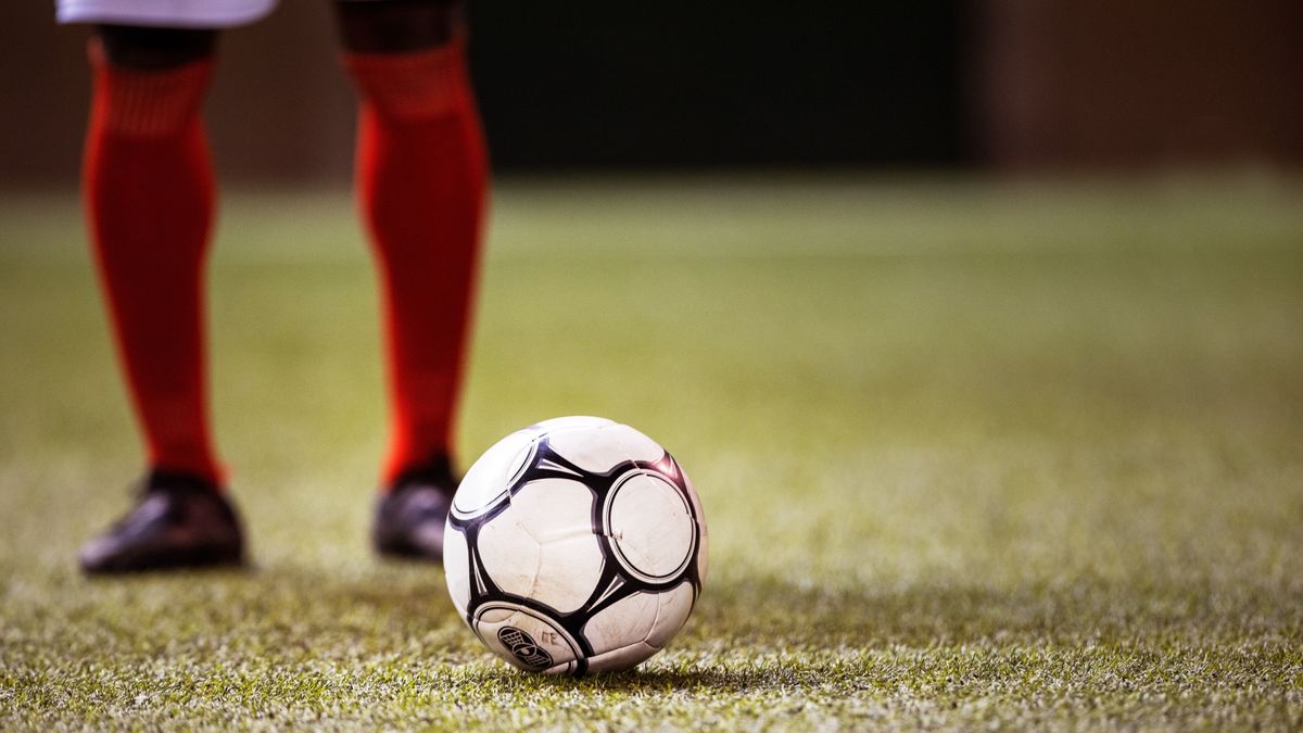 Professional soccer player prepares to strike soccer ball with his cleat on stadium field