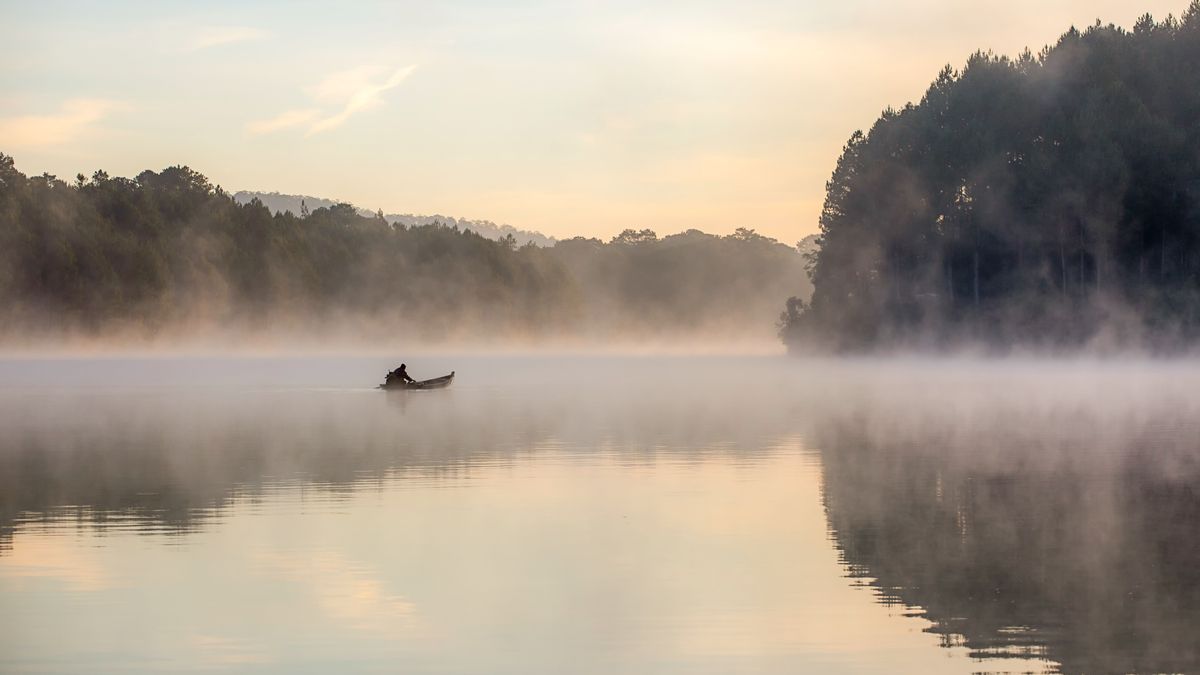 the abstract of lonely fishermen fishing on the fog lake at sunrise