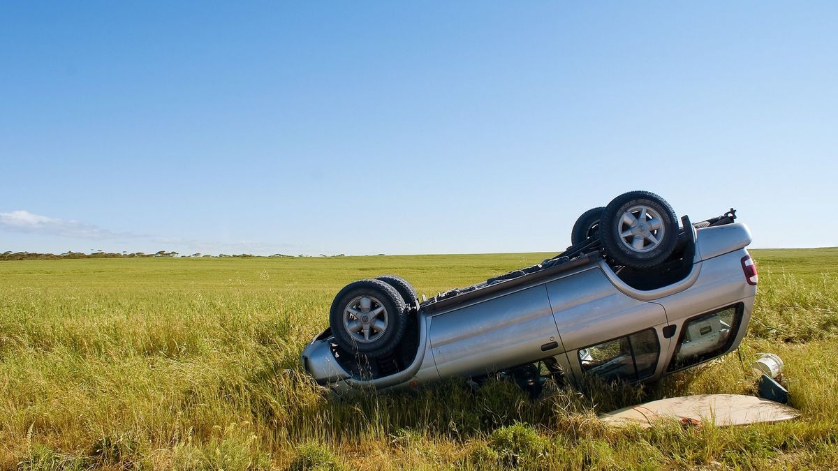 Car crashed on country road with field and sky
