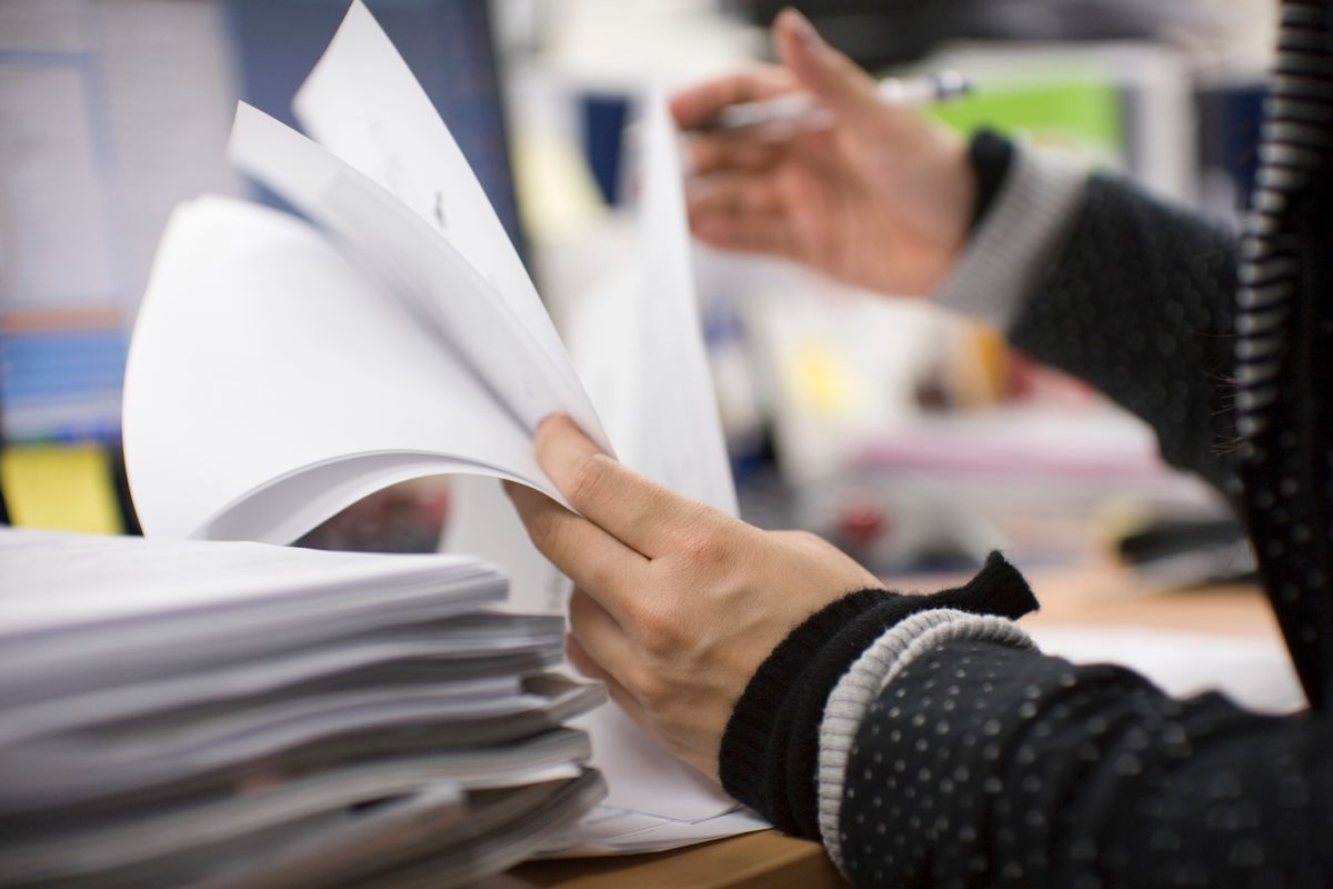 Office worker checking documents on desk, mid section, side view