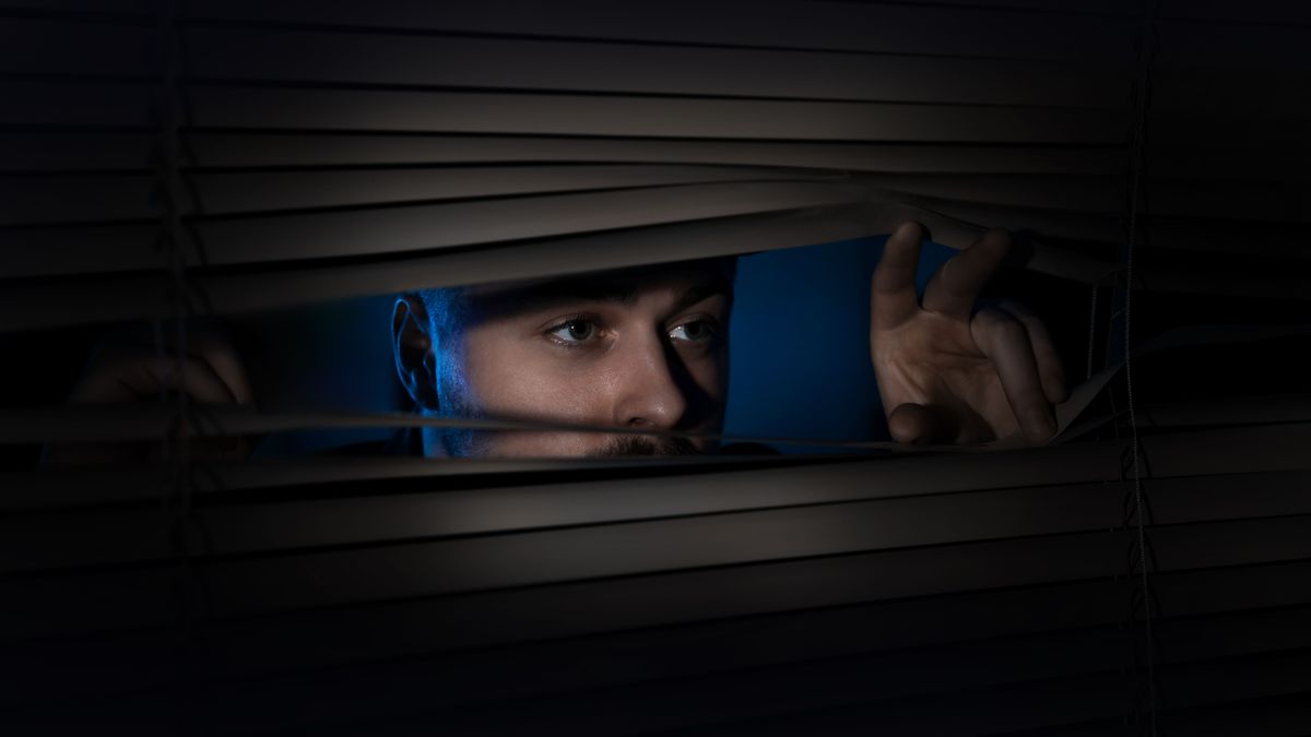 Worried,Man,Looking,Through,Window,Blinds,Into,Darkness.,Paranoia,Concept