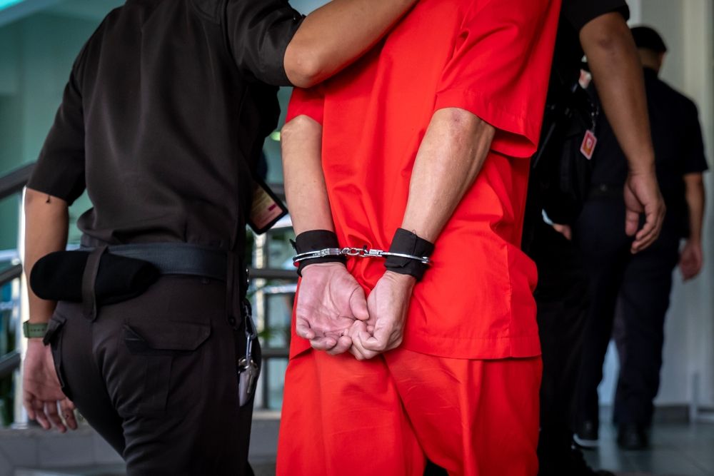 Arrested,Male,Criminal,In,Prison,Uniform,And,Handcuffs,Is,Brought